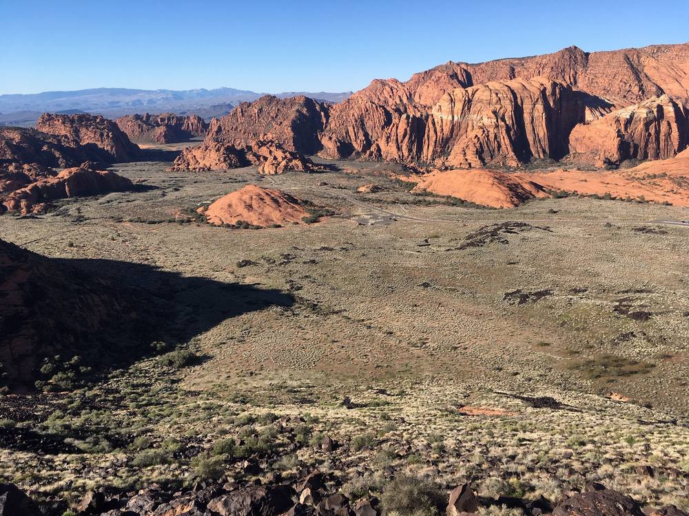 Red Navajo sandstone cliffs rising above black lava rock and desert sage in Snow Canyon State Park near Ivins, Utah
